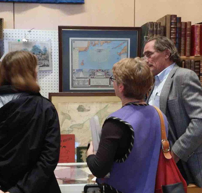 Two fairgoers talking with exhibitor William Hutchison, bookseller and ephemera specialist, based in Mendenhall, Pennsylvania